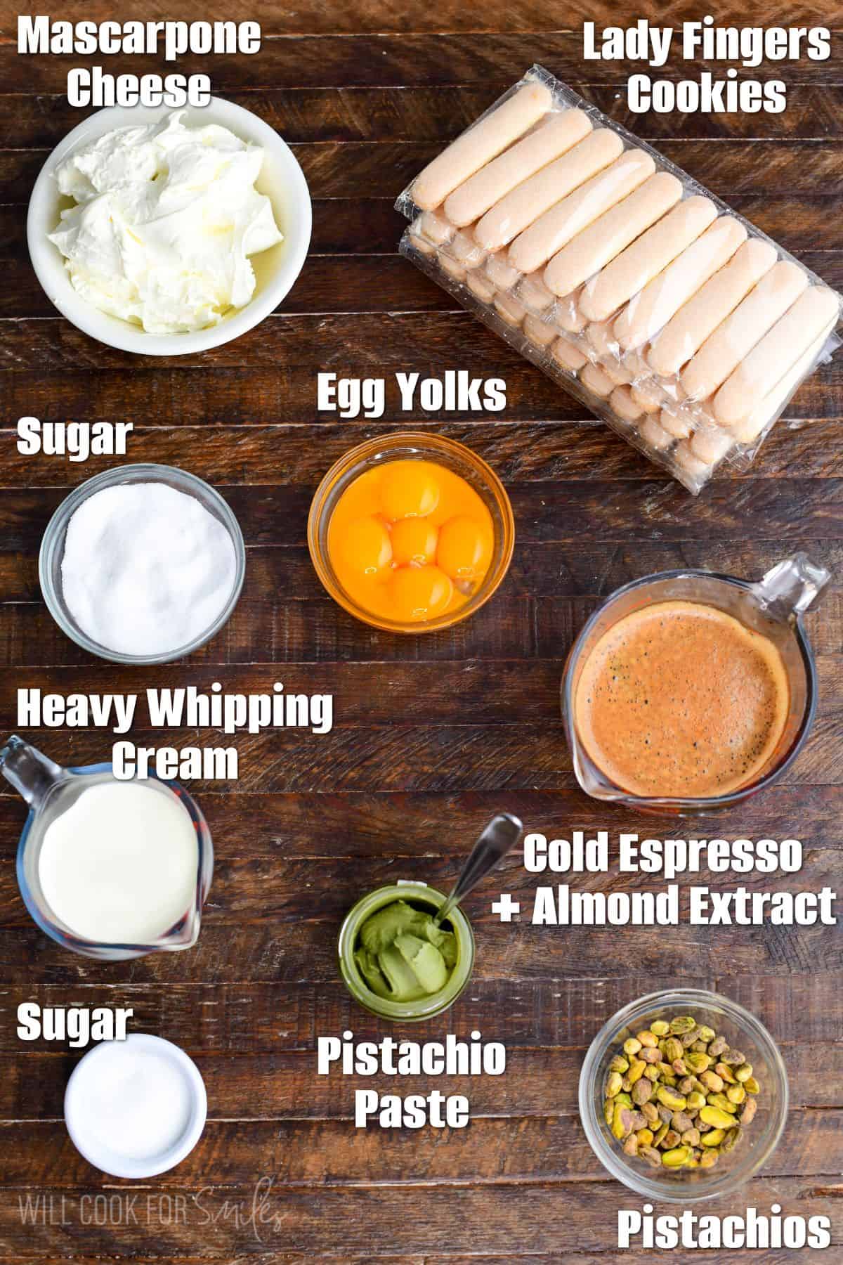 Labeled ingredients for pistachio tiramisu on a wood surface.