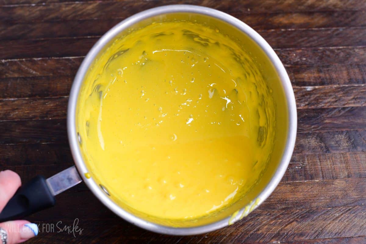 Cooked egg yolk custard mixture in a saucepan, thickened and smooth after whisking.