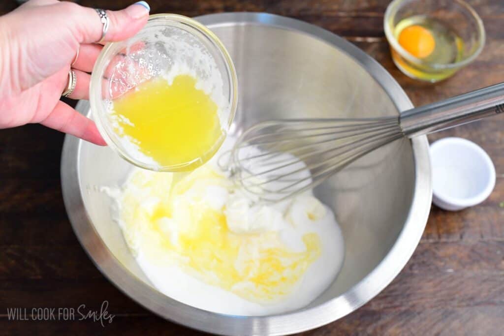 Melted butter being added to cream cheese and sugar in a mixing bowl to make red velvet cream cheese cookies.