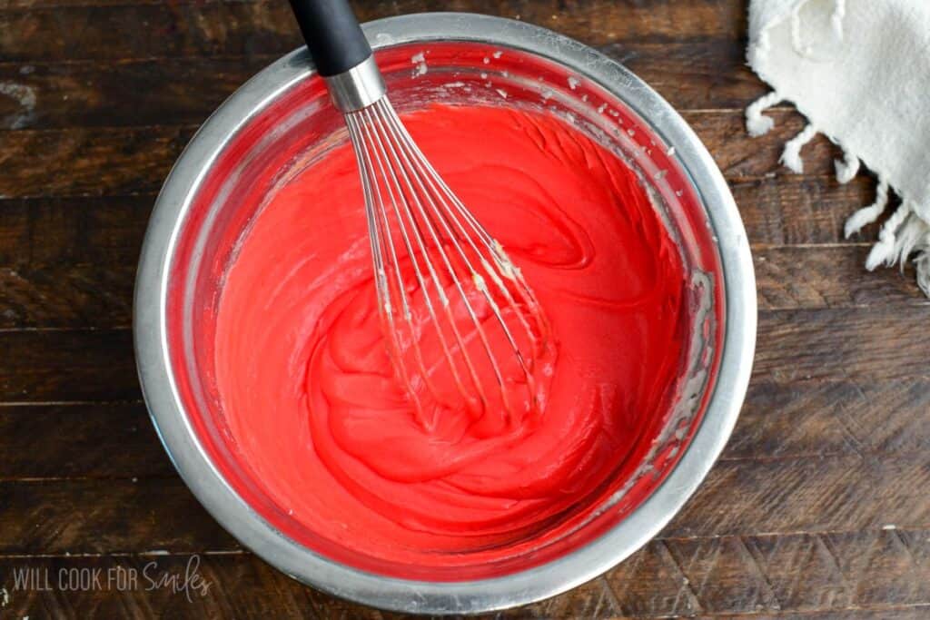 Red velvet cookie batter mixed with red food coloring in a bowl for red velvet cream cheese cookies.