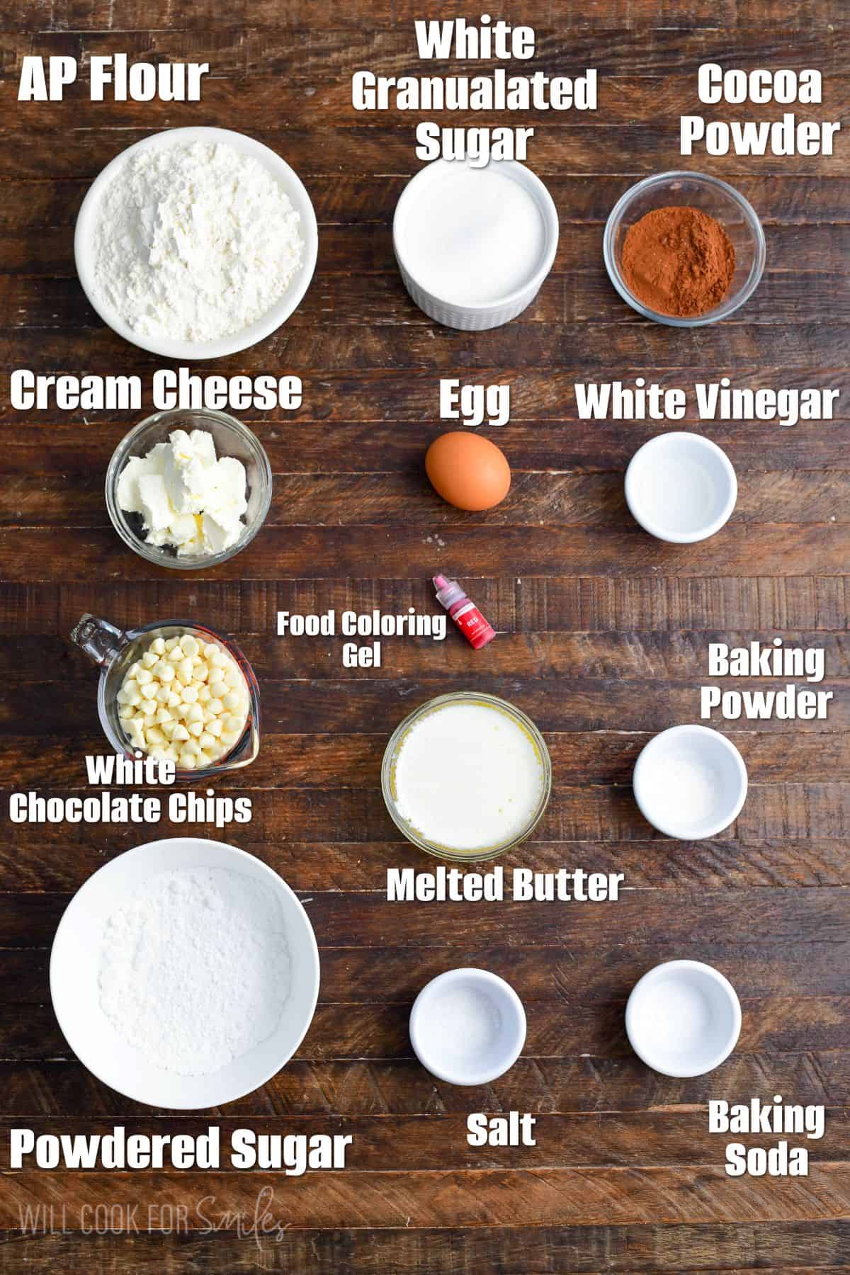 Labeled ingredients for red velvet cream cheese cookies on a wood surface.