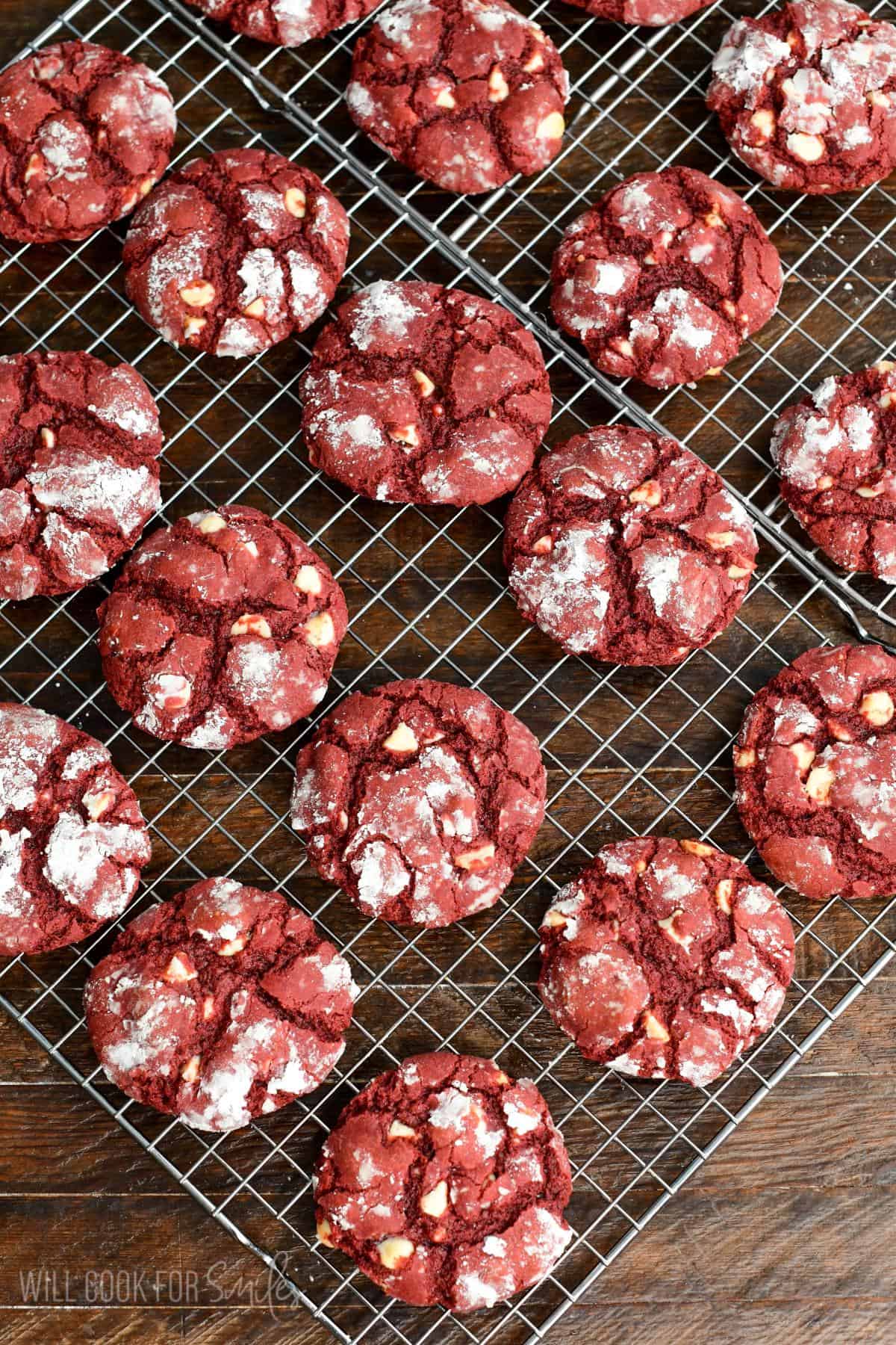 Baked red velvet cream cheese cookies with white chocolate chips cooling on a wire rack.