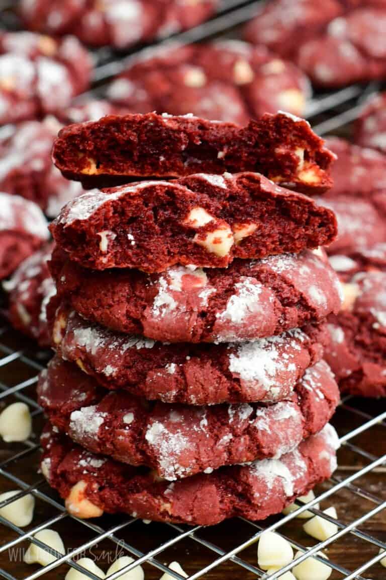 Stack of red velvet cream cheese cookies with one broken open, showing the soft center and white chocolate chips.