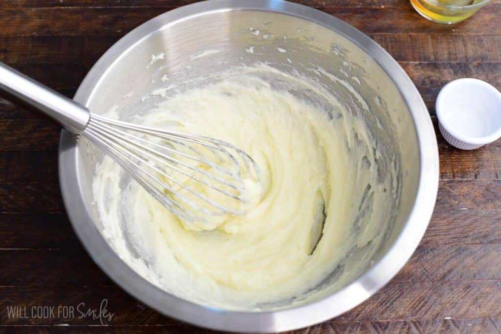 Butter, sugar, and cream cheese whisked together in a mixing bowl for red velvet cream cheese cookies.