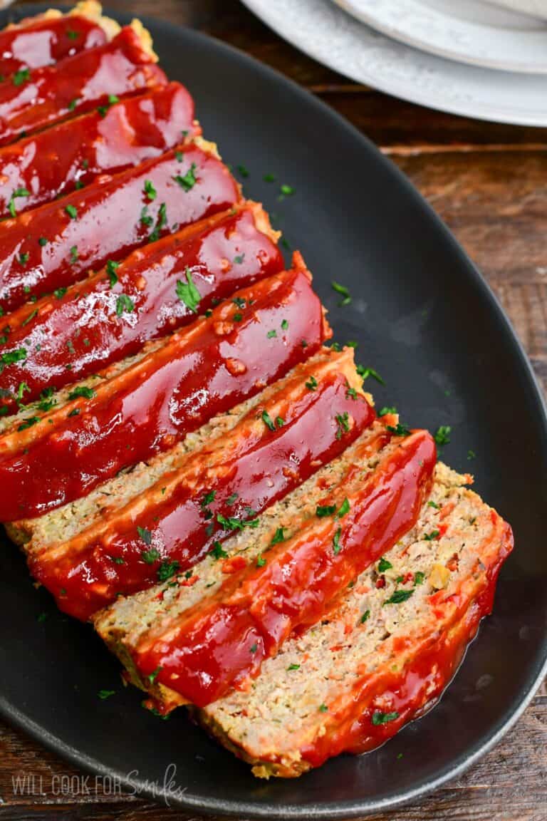 juicy and tender turkey meatloaf with honey balsamic ketchup glaze sliced on a black platter.